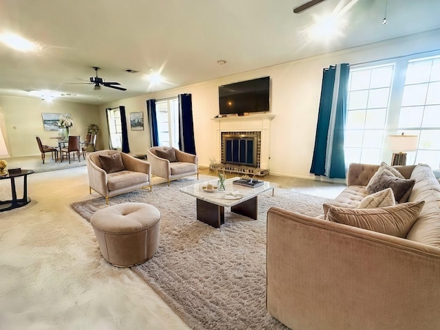 living room featuring carpet floors, a wealth of natural light, a brick fireplace, and a ceiling fan