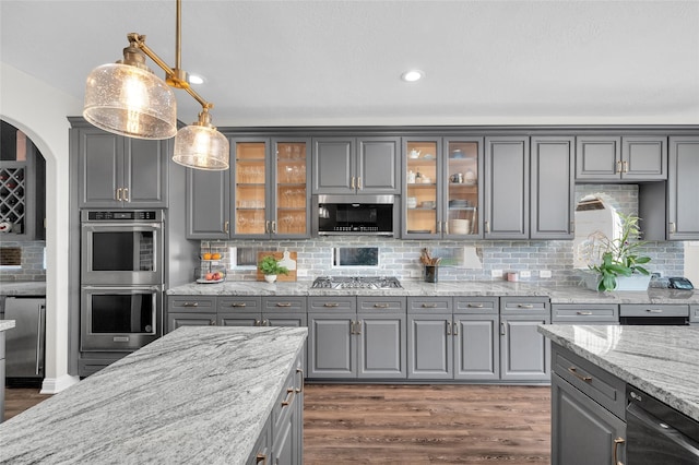 kitchen featuring dark wood-type flooring, light stone counters, hanging light fixtures, gray cabinets, and stainless steel appliances