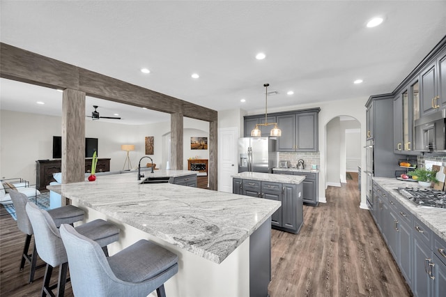 kitchen with gray cabinets, sink, hanging light fixtures, stainless steel appliances, and a spacious island