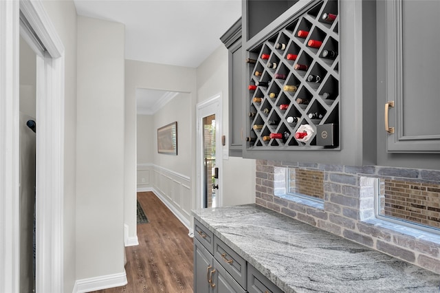 wine cellar featuring dark hardwood / wood-style flooring, crown molding, and bar