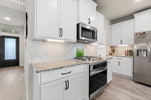 kitchen featuring decorative backsplash, light hardwood / wood-style flooring, white cabinets, and appliances with stainless steel finishes