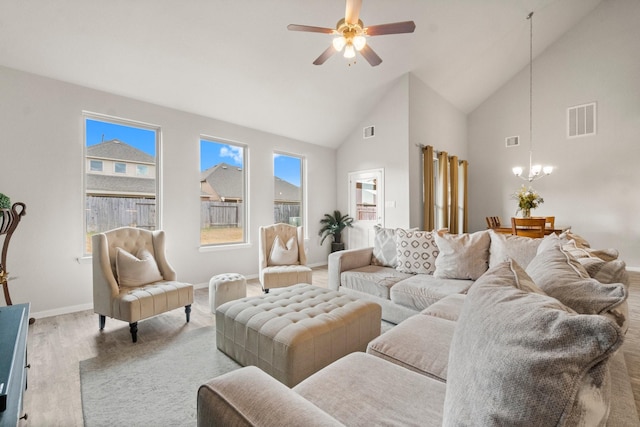 living room featuring ceiling fan with notable chandelier, light hardwood / wood-style flooring, and high vaulted ceiling