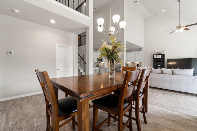 dining area featuring ceiling fan with notable chandelier, high vaulted ceiling, and light hardwood / wood-style floors