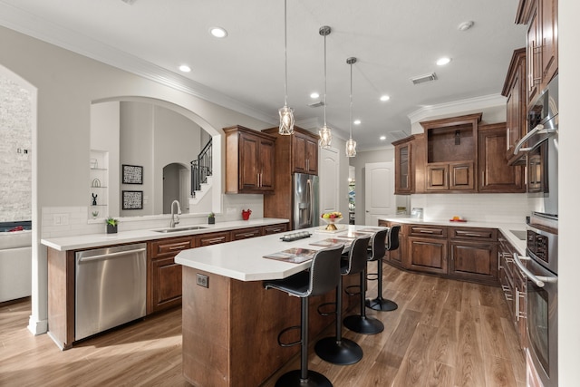 kitchen with appliances with stainless steel finishes, decorative light fixtures, tasteful backsplash, sink, and a center island