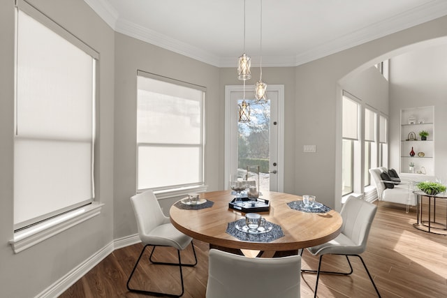 dining area with crown molding, a notable chandelier, and hardwood / wood-style flooring