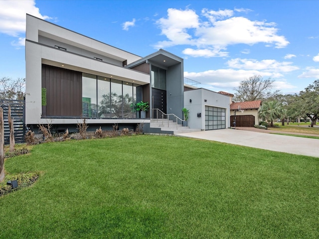 contemporary house featuring a garage, a front yard, concrete driveway, and stucco siding