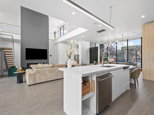 kitchen with a sink, white cabinetry, modern cabinets, a kitchen bar, and a center island with sink