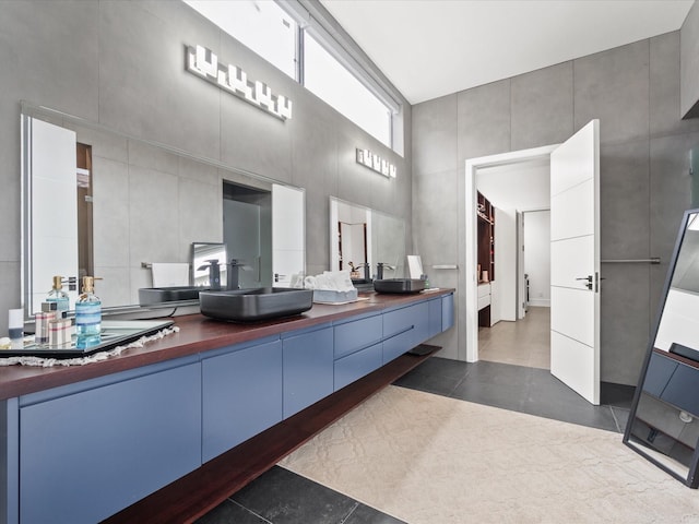 bathroom featuring double vanity, tile patterned flooring, a towering ceiling, and a sink