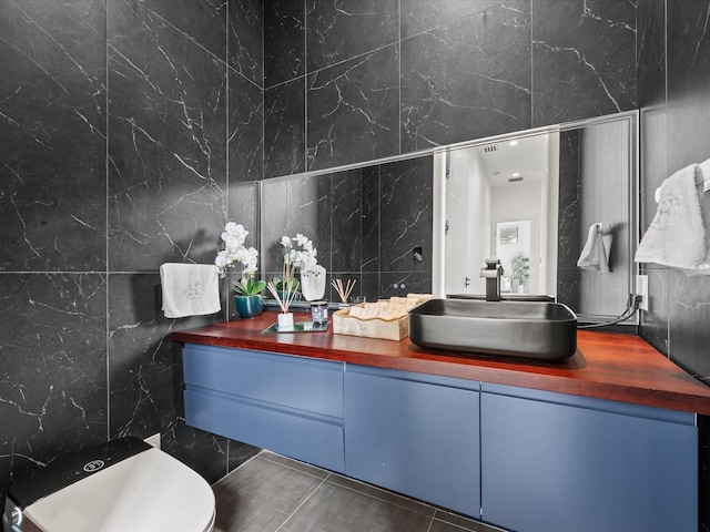 half bathroom featuring tile walls, vanity, and toilet