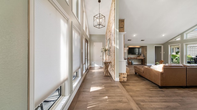 corridor with hardwood / wood-style floors, a towering ceiling, and a notable chandelier