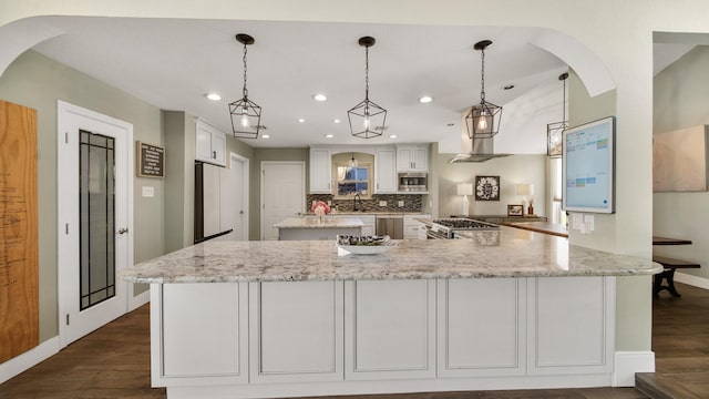 kitchen featuring appliances with stainless steel finishes, pendant lighting, light stone countertops, decorative backsplash, and white cabinets