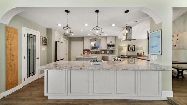 kitchen featuring dark hardwood / wood-style floors, pendant lighting, stainless steel appliances, light stone countertops, and white cabinets