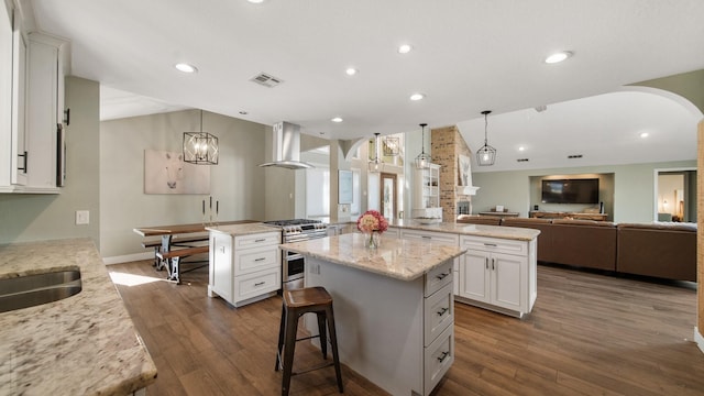 kitchen featuring white cabinetry, decorative light fixtures, a kitchen island, and exhaust hood