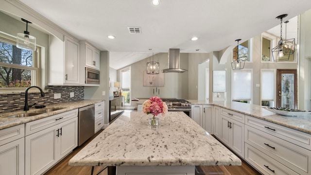 kitchen featuring ventilation hood, light stone countertops, a kitchen island, and stainless steel appliances