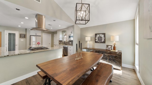 dining area featuring vaulted ceiling, a wealth of natural light, a chandelier, and light wood-type flooring