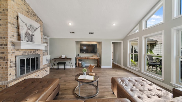 living room with wood-type flooring, a brick fireplace, and high vaulted ceiling