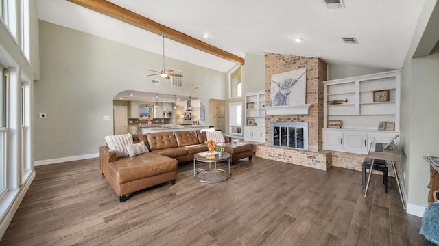 living room featuring beamed ceiling, wood-type flooring, a brick fireplace, and high vaulted ceiling