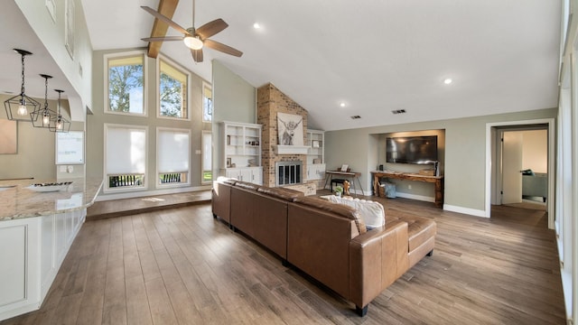 living room featuring a brick fireplace, light hardwood / wood-style floors, high vaulted ceiling, and ceiling fan