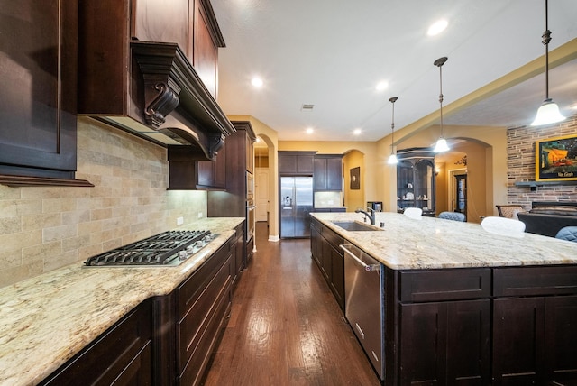 kitchen featuring sink, decorative light fixtures, a large island with sink, appliances with stainless steel finishes, and decorative backsplash