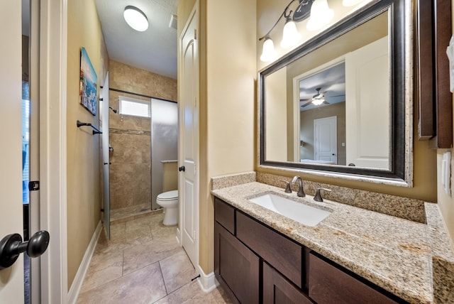 bathroom featuring vanity, a tile shower, and toilet