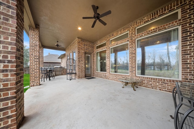 view of patio with exterior bar, area for grilling, and ceiling fan