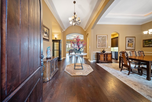 entrance foyer featuring crown molding, vaulted ceiling, dark wood-type flooring, and an inviting chandelier