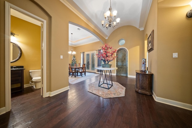 entrance foyer featuring vaulted ceiling, ornamental molding, dark hardwood / wood-style floors, and a chandelier