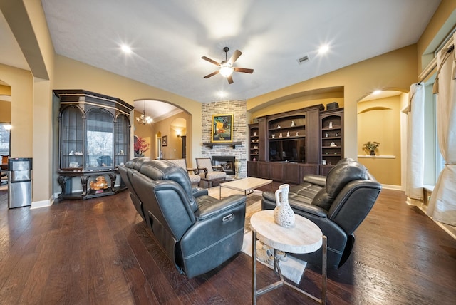 living room with dark hardwood / wood-style flooring, ceiling fan with notable chandelier, and a fireplace