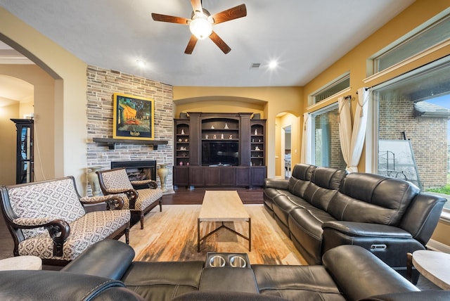 living room with a fireplace, ceiling fan, and light wood-type flooring