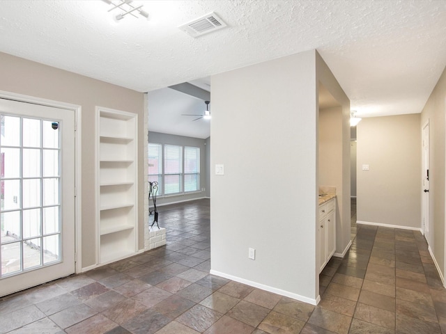 hall with built in shelves and a textured ceiling