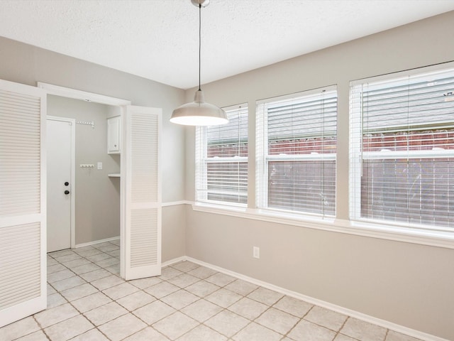 unfurnished dining area with light tile patterned flooring and a textured ceiling