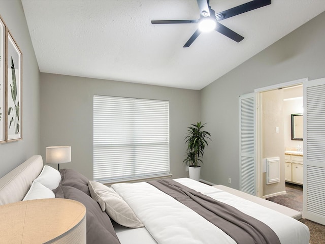 bedroom with dark carpet, ensuite bath, vaulted ceiling, and ceiling fan