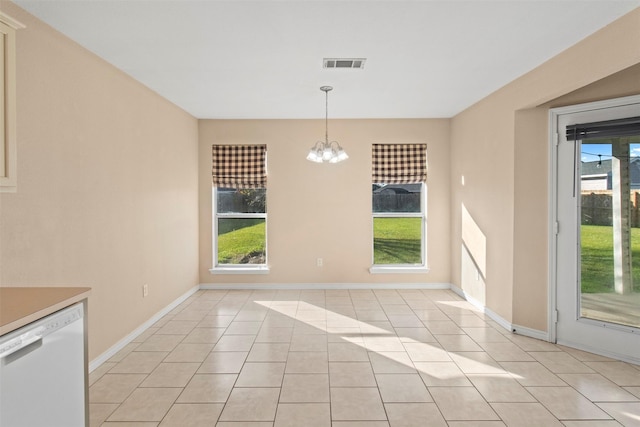 unfurnished dining area featuring an inviting chandelier, light tile patterned floors, and a healthy amount of sunlight