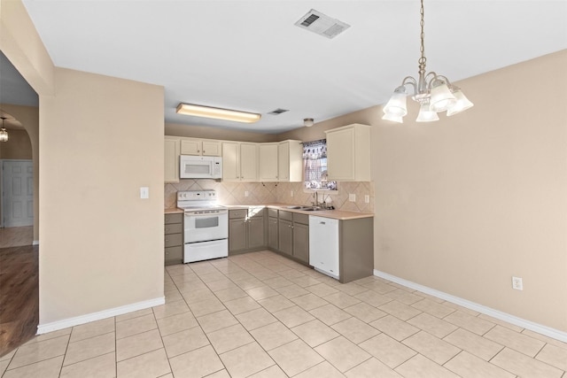 kitchen with pendant lighting, sink, white appliances, light tile patterned floors, and a chandelier