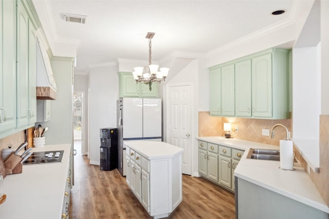 kitchen with white refrigerator, sink, pendant lighting, and light hardwood / wood-style floors