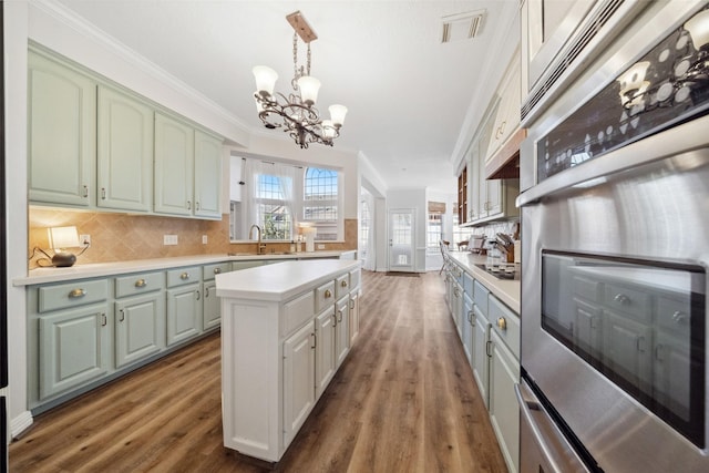 kitchen featuring pendant lighting, crown molding, a center island, tasteful backsplash, and oven