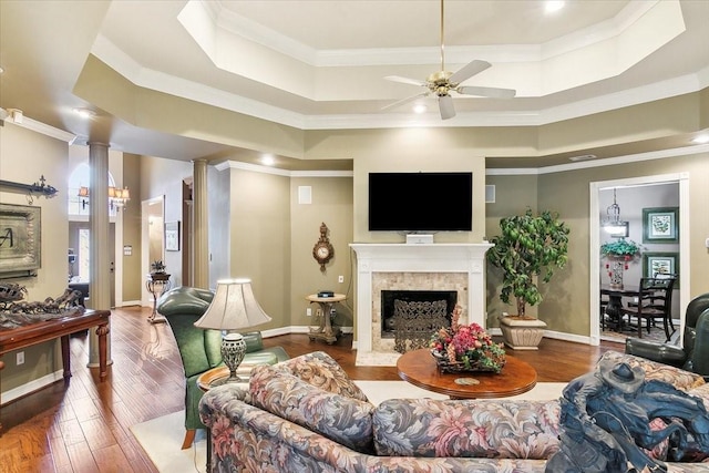 living room with ornate columns, crown molding, hardwood / wood-style floors, and a tray ceiling