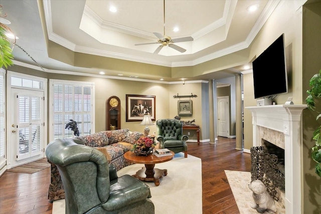 living room featuring a raised ceiling, crown molding, a premium fireplace, and dark wood-type flooring