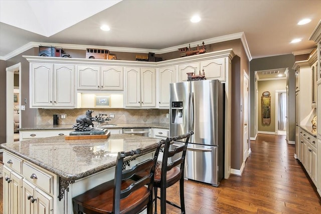 kitchen with appliances with stainless steel finishes, a center island, light stone countertops, and backsplash