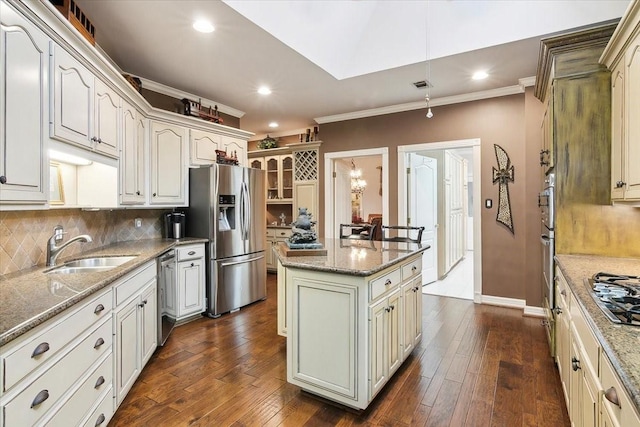 kitchen with appliances with stainless steel finishes, sink, dark hardwood / wood-style flooring, a center island, and light stone countertops