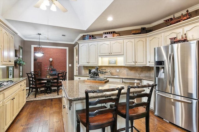 kitchen with tasteful backsplash, light stone counters, hanging light fixtures, a kitchen island, and stainless steel appliances