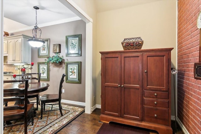 dining area featuring ornamental molding, brick wall, and dark hardwood / wood-style flooring