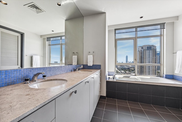 bathroom with vanity, plenty of natural light, tile patterned floors, and tiled bath