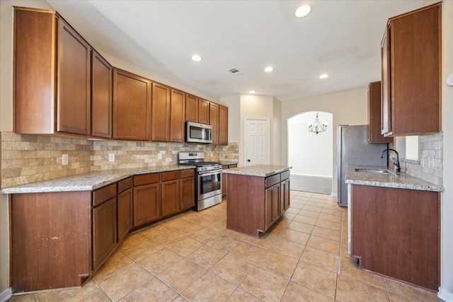 kitchen with stainless steel appliances, light stone countertops, and a kitchen island