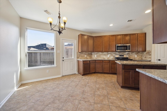 kitchen with backsplash, hanging light fixtures, light tile patterned floors, stainless steel appliances, and light stone countertops