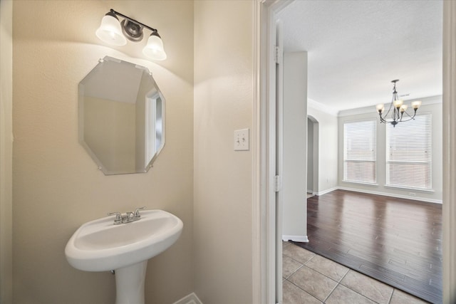 bathroom featuring tile patterned flooring, crown molding, and an inviting chandelier