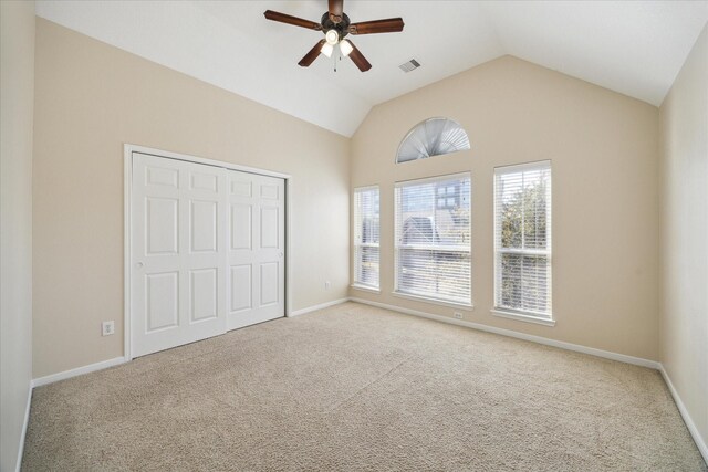 unfurnished bedroom with ceiling fan, lofted ceiling, a closet, and light carpet