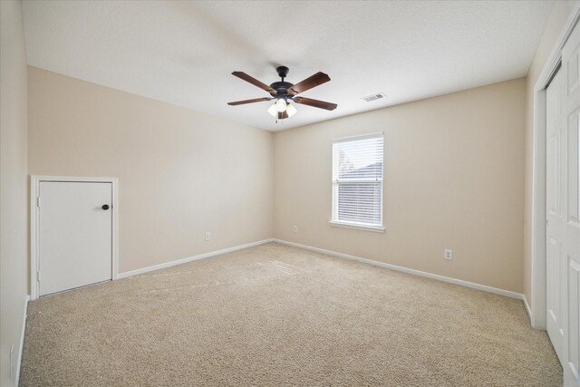 spare room featuring light colored carpet and ceiling fan