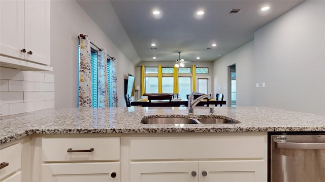 kitchen featuring white cabinetry, sink, stainless steel dishwasher, and light stone countertops