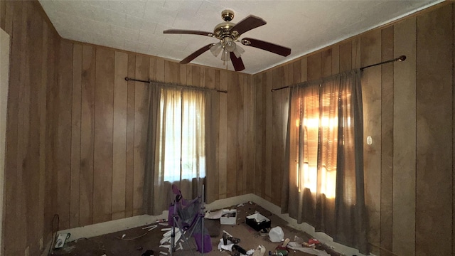 misc room with ceiling fan and wood walls